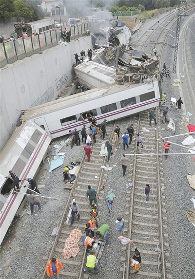 24日，救援人員在西班牙列車(chē)脫軌現(xiàn)場(chǎng)。一節(jié)車(chē)廂被強(qiáng)大的慣性拋上鐵道邊的高臺(tái)。