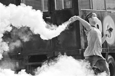 12月2日，泰國曼谷，一名反政府示威者在總理府附近向負(fù)責(zé)執(zhí)勤的警察投擲催淚彈。英拉請求示威者不要再試圖占領(lǐng)政府工作部門，不要逼迫政府工作人員選邊站。