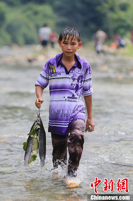 圖為7月9日，一名男孩在鬧魚節(jié)活動中抓到了兩條魚。譚凱興 攝