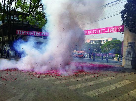 市民在普洱市主干道振興大道的金孔雀交通運(yùn)輸集團(tuán)有限公司門(mén)前燃放鞭炮，公司門(mén)前掛著“貪腐份子沈培平被查處，罪有應(yīng)得，大快人心?！钡臈l幅