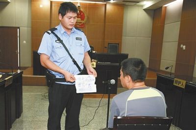 昨日庭審中，法警向趙某出示其扎完車胎后所留辱罵公司的紙條。通訊員 李秀文 攝
