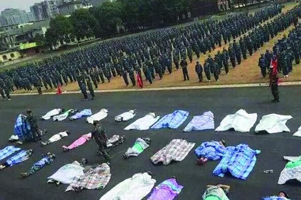 20多名女生躺在瀝青跑道上，身上嚴(yán)嚴(yán)實(shí)實(shí)地裹著棉被，接受太陽(yáng)的照曬。