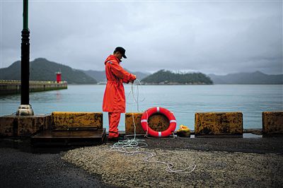7月6日，韓國珍島，一名海岸警察在港口系救生圈。4月，客輪在珍島近海發(fā)生沉船事故后，仍有11人下落不明。