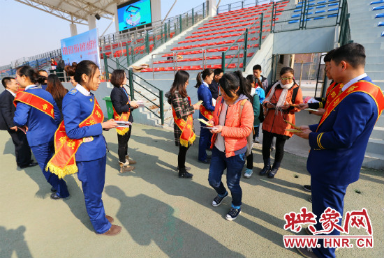 活動現(xiàn)場工作人員給同學(xué)們發(fā)放宣傳冊、環(huán)保袋。