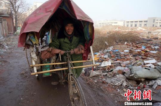 圖為老人走出窩棚，推著三輪車準(zhǔn)備出去撿拾廢品。周小云 攝