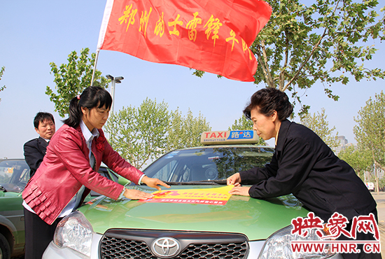 　　授旗結(jié)束后，首都的士雷鋒車(chē)隊(duì)王鳳進(jìn)隊(duì)長(zhǎng)（右）與鄭州的的哥的姐在車(chē)身上貼上標(biāo)識(shí)。