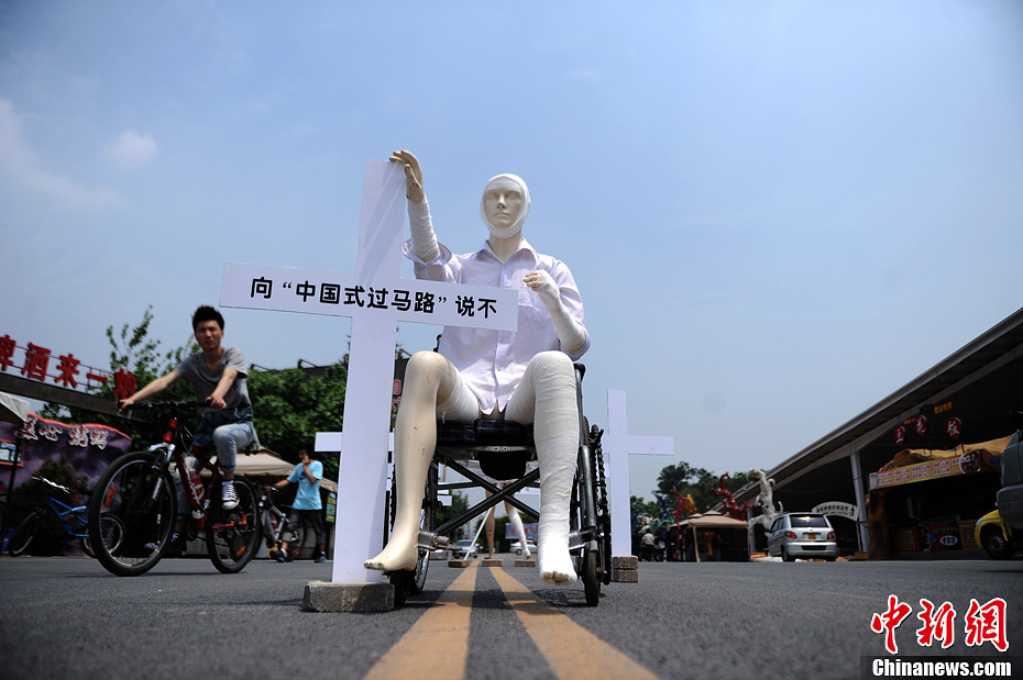 4月16日，重慶市洋人街上擺放著兩個(gè)受了傷的塑料人像“模特”，旁邊十字架上寫(xiě)著向“中國(guó)式過(guò)馬路”說(shuō)不
