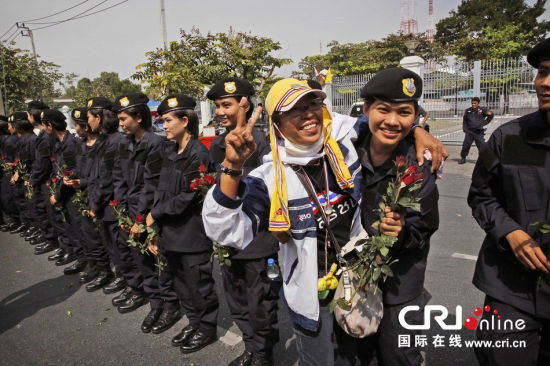 2013年12月03日,曼谷總理府與曼谷警署允許反政府示威民眾進入,雙方進入暫時“停戰(zhàn)”狀態(tài)迎接泰王生日。曼谷警察總署,女警們手持鮮花送給反政府示威民眾。圖片來源:Manish Swarup/東方IC