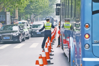 省人民醫(yī)院南門的路中間擺放反光錐，交警示意由西向東車輛從前方繞行。