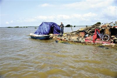 15日，因黑龍江水位上漲，一位轉移家中物資被困屋頂?shù)睦先讼蛎窬笾?。新華社發(fā)