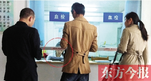 昨日，鄭州市二七區(qū)疾控中心辦證大廳，血檢窗口內(nèi)一名女工作人員，邊接受辦證者咨詢邊看報紙