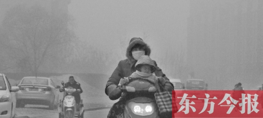 12月8日，鄭州市未來路上，一位市民帶著孩子在霧中騎行
