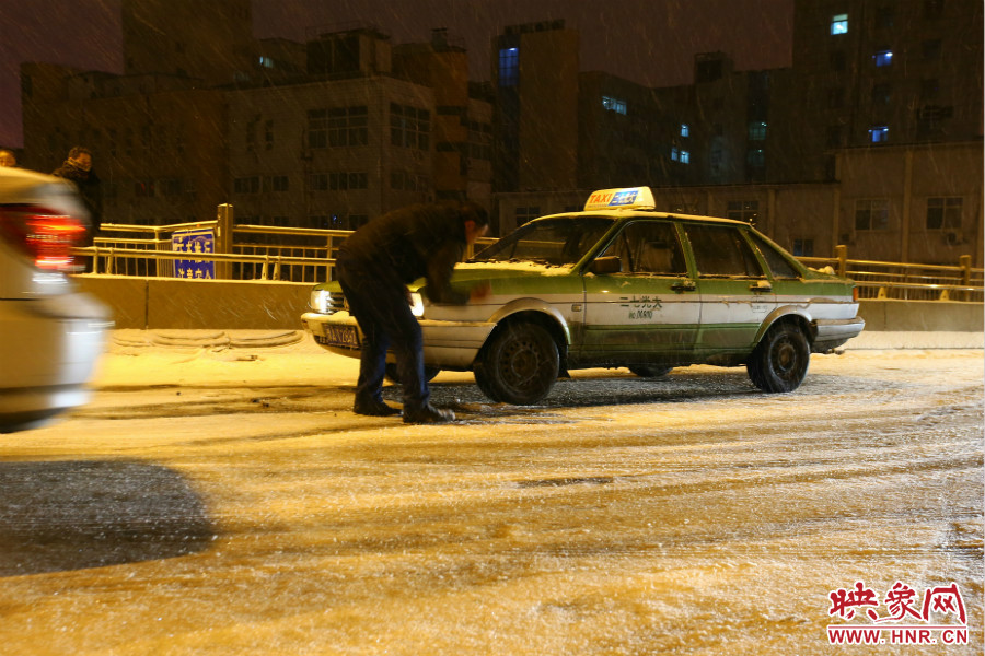 一位出租車司機(jī)在車輪前灑上雪，希望能增加輪胎的摩擦力。