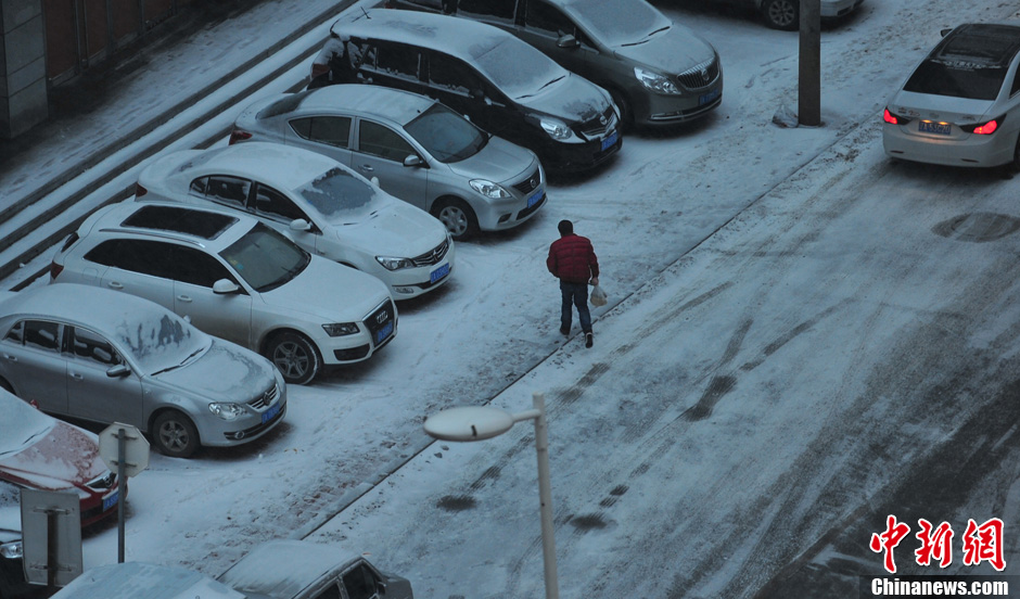 11月18日，行人在沈陽(yáng)街頭的積雪中穿行。