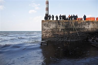 昨日，山東青島，清污人員正在海邊清理油污。