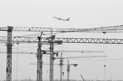 空中是起飛的飛機(jī)，下面是T2航站樓工地上林立的塔吊