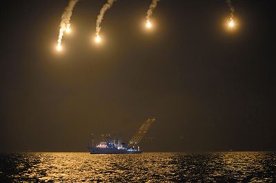 22日，搜救人員在照明彈的光亮下連夜搜救。