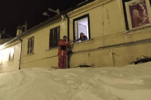 一個居民站在積雪上，可以與一名二樓鄰居在窗口握手。（來源：意大利氣象局）