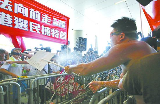 17日，在香港立法會(huì)外，一名反對(duì)政改的男子向支持派人群投擲標(biāo)牌。