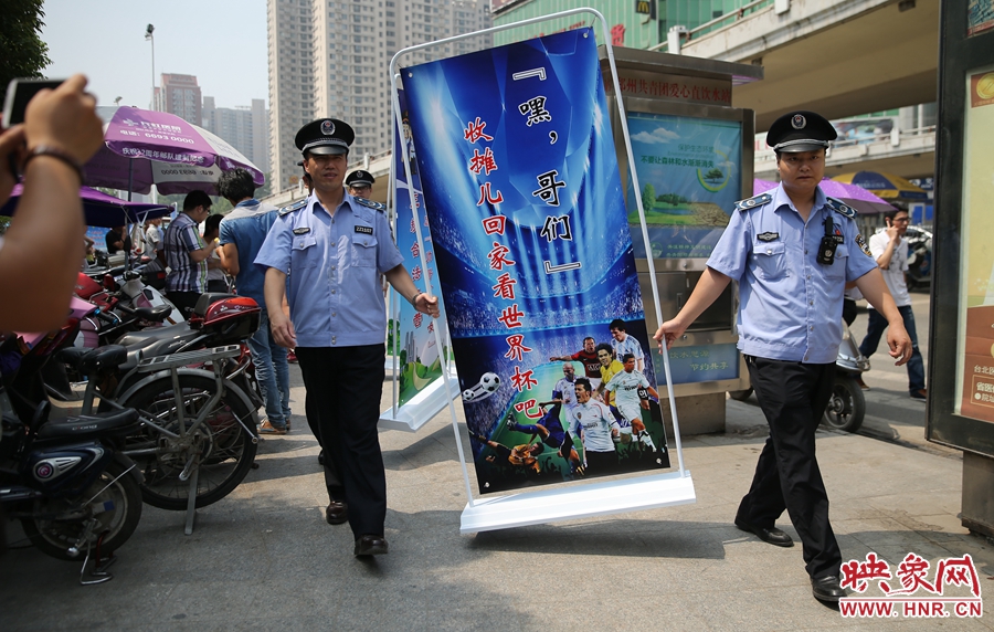 7月2日上午，鄭州市紫荊山地鐵站出入口，執(zhí)法人員抬著寫有勸導(dǎo)語的宣傳板，前往占道經(jīng)營(yíng)攤位“圍觀執(zhí)法”