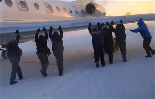 　伊加爾市一架客機起飛前被凍在了跑道上。飛機上的乘客不得不下來推飛機。