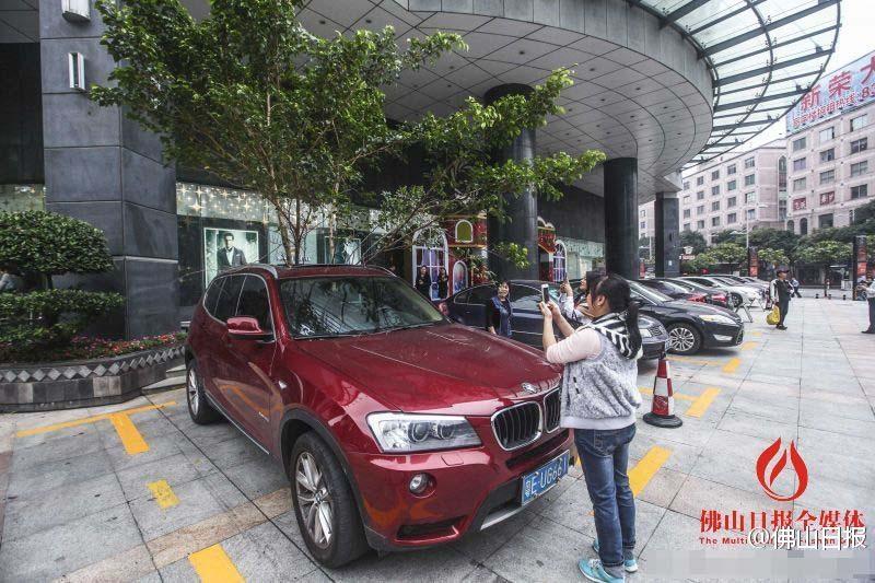 一輛停在停車位上的寶馬轎車，被墜落的樹枝砸中，樹枝徑直插入車內，現場引發(fā)不少市民圍觀拍照。