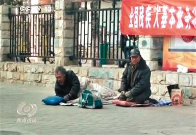 工人體育場(chǎng)北路，兩位乞討者路邊乞討，并輪流扮成“病人”（躺地者）。 央視截圖