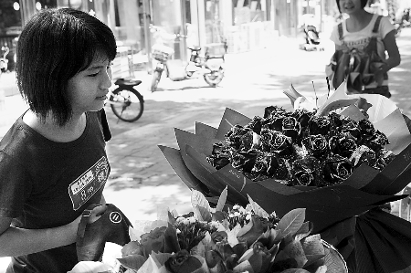 鄭州市農(nóng)業(yè)路一家花店擺放的玫瑰花吸引著一位過往女孩。